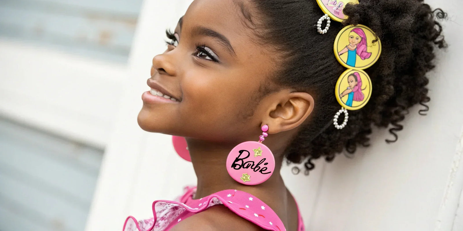 Smiling girl wearing Barbie earrings and hair accessories, officially licensed from LuvHer Shop