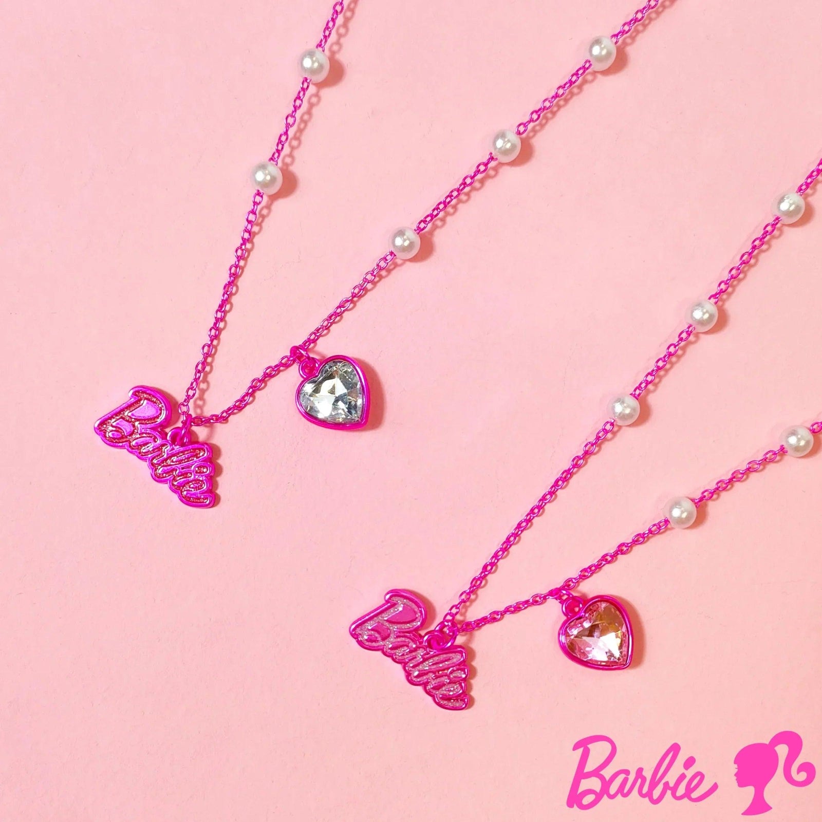 Barbie Heart Crystal Necklace set with pink chain, pearl accents, and Barbie logo charms on pink background