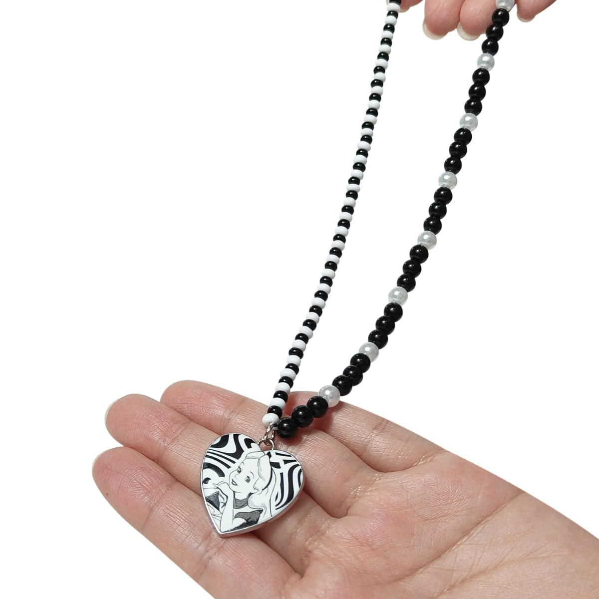 Alice in Wonderland beaded heart necklace held in hand, black and white girls' jewelry