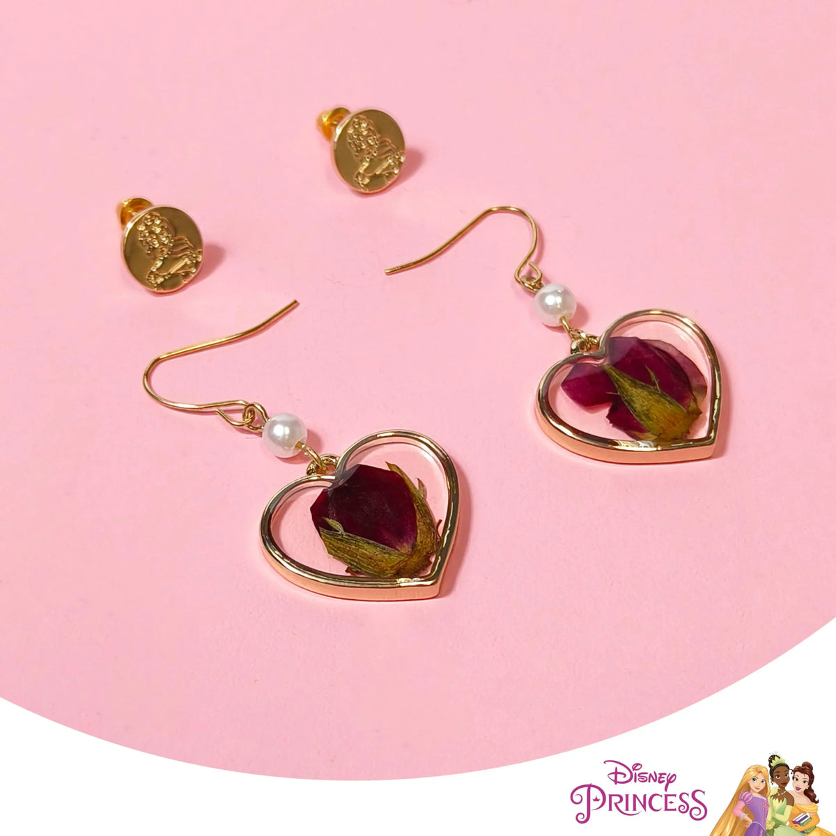 Disney Princess Rose Gold Heart Earrings with dried rosebud, pearl accents, and matching gold studs on pink background