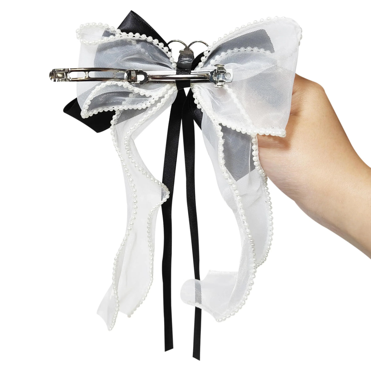 LuvHer Shop black and white lace hair bow with pearl trim and barrette, held in hand