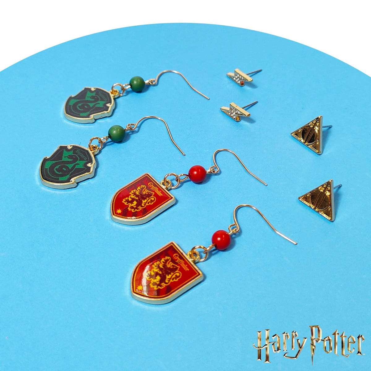Harry Potter earring set with Gryffindor, Slytherin, and Deathly Hallows designs on blue background