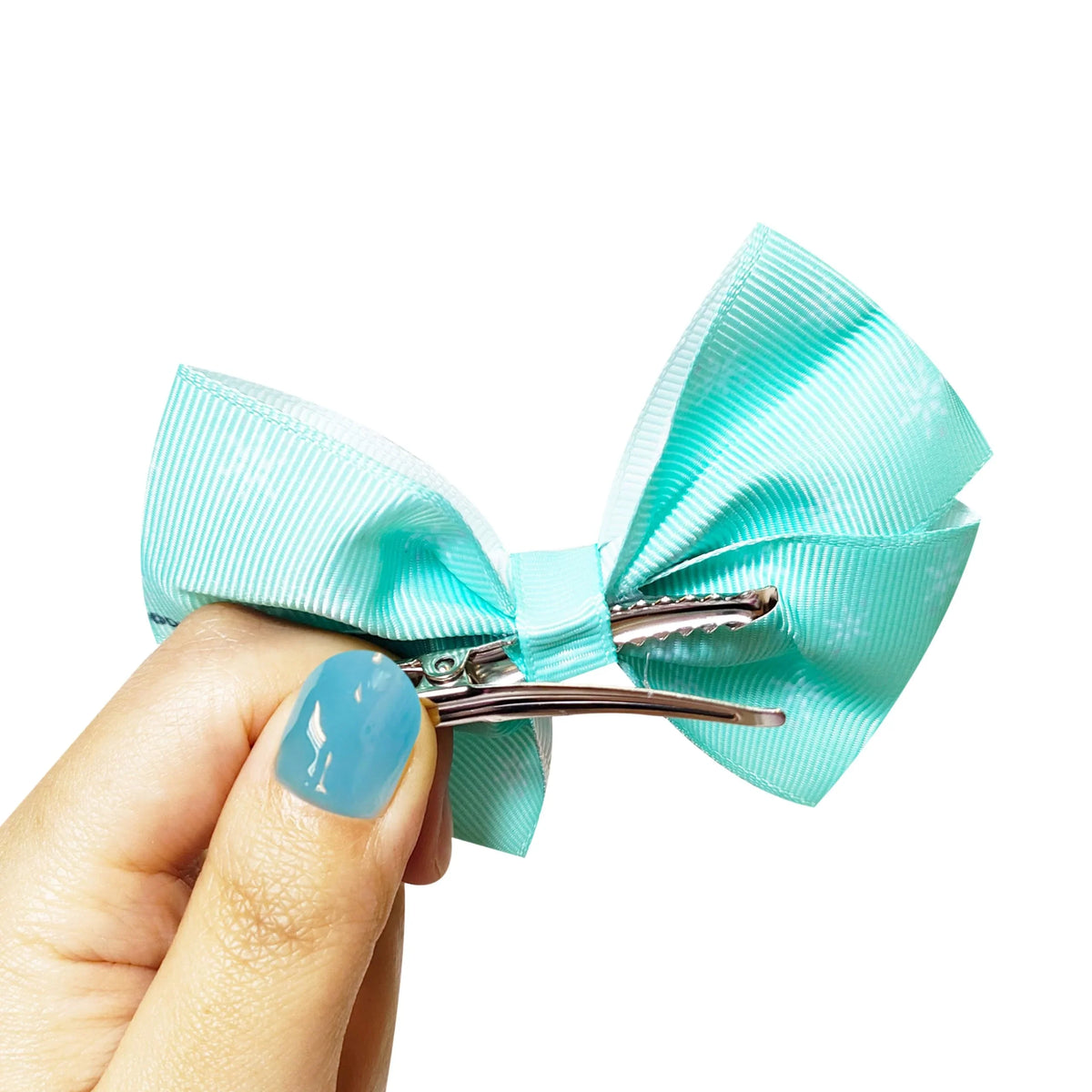 Turquoise hair bow clip from LuvHer Shop held in hand, girls' accessory for hair styling