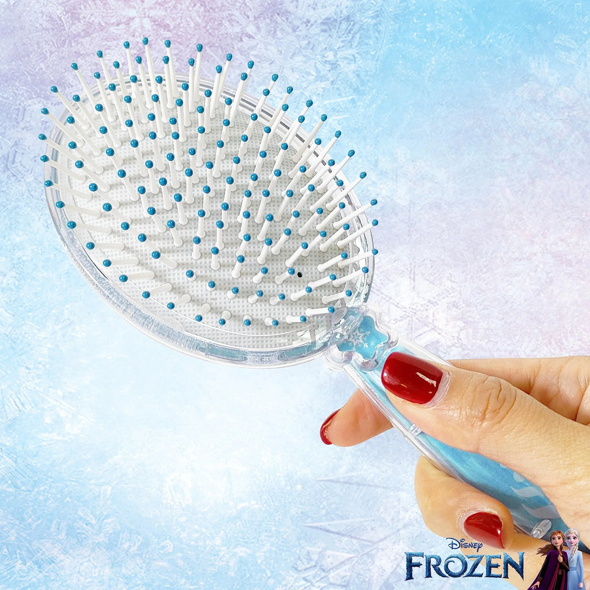 Disney Frozen hair brush for girls with blue and white bristles, held in hand, on icy background